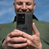 Bradunkin holding a phone in a green shirt